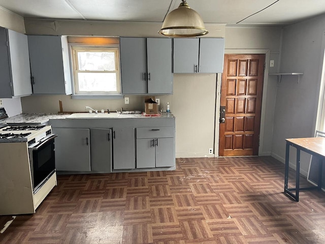 kitchen with decorative light fixtures, white gas stove, gray cabinets, light countertops, and baseboards