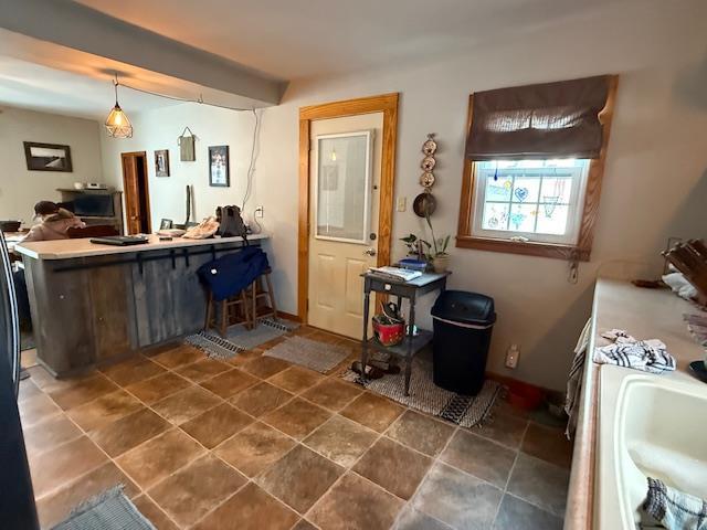 kitchen featuring hanging light fixtures, a sink, a peninsula, and baseboards