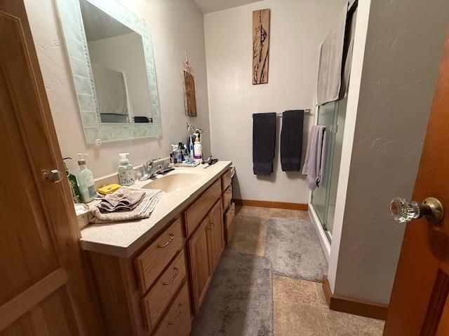 bathroom with a stall shower, vanity, and baseboards