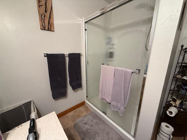 full bath featuring a shower stall and baseboards