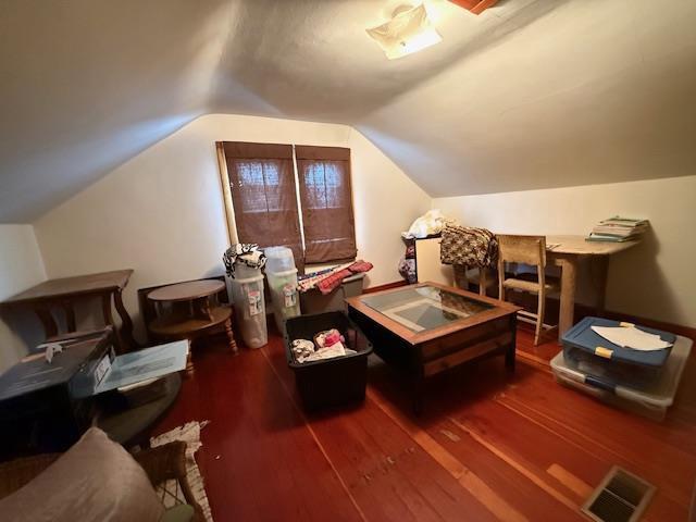 interior space with visible vents, vaulted ceiling, and wood finished floors