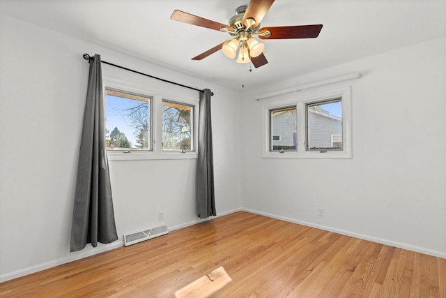 spare room with light wood-type flooring, visible vents, and baseboards