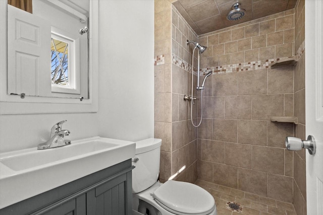 bathroom with toilet, a tile shower, and vanity