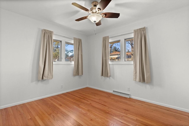 empty room featuring a healthy amount of sunlight, baseboards, and wood finished floors