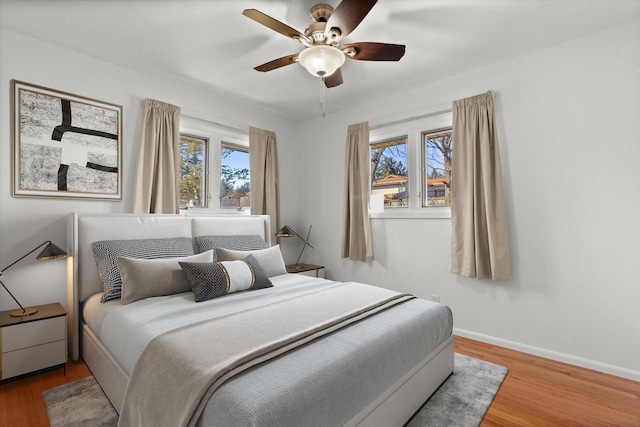 bedroom featuring a ceiling fan, baseboards, and wood finished floors