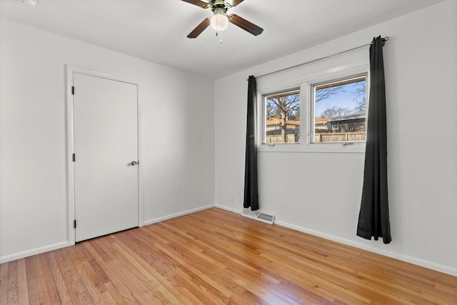 empty room with light wood-style flooring, visible vents, ceiling fan, and baseboards