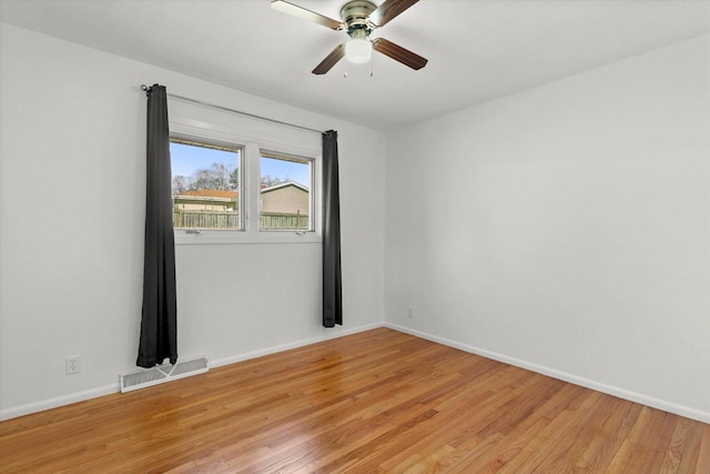 empty room with light wood-style flooring, a ceiling fan, visible vents, and baseboards