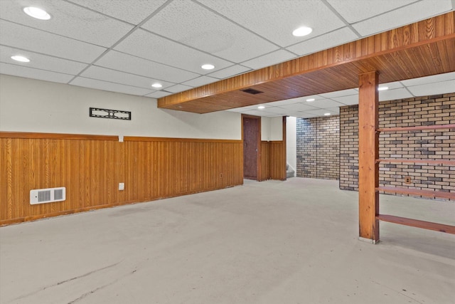 finished below grade area with a drop ceiling, recessed lighting, wood walls, visible vents, and wainscoting