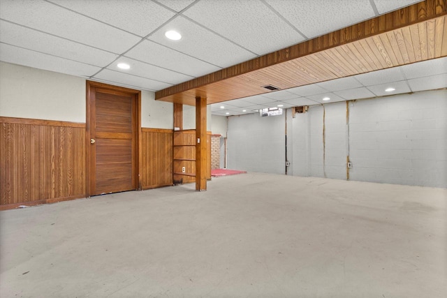 finished basement featuring recessed lighting, a wainscoted wall, a paneled ceiling, and wooden walls