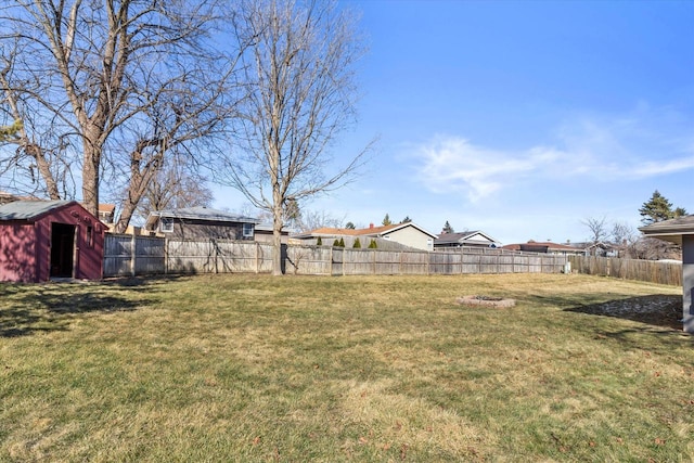 view of yard with an outbuilding, a fenced backyard, and a storage unit