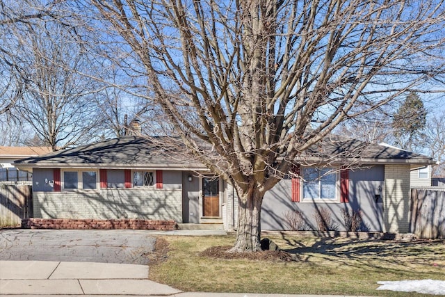 ranch-style house featuring a chimney, fence, and brick siding