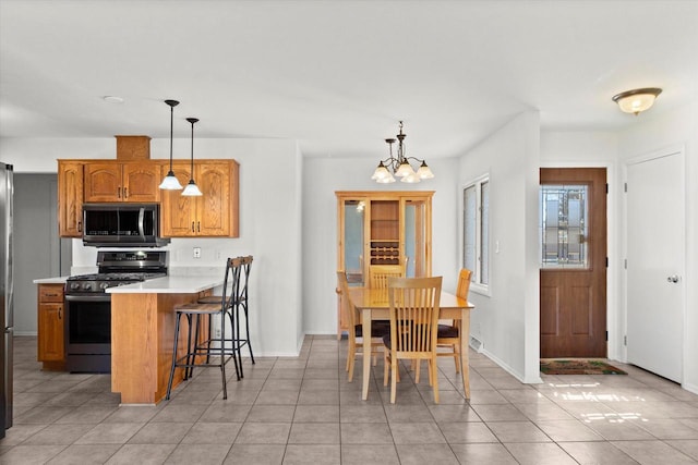 kitchen with a peninsula, a breakfast bar, light countertops, stainless steel microwave, and gas stove