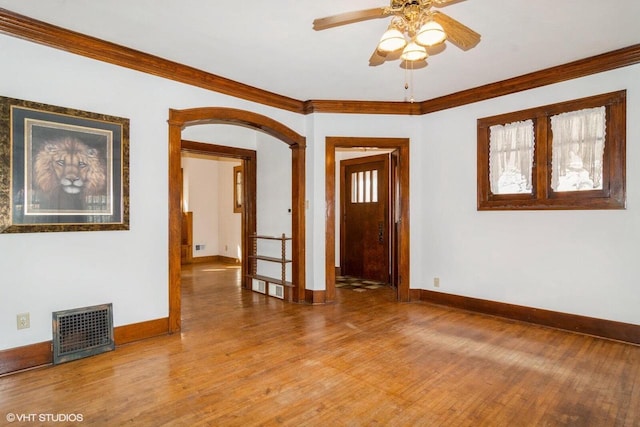 foyer entrance with light wood finished floors, visible vents, arched walkways, and crown molding