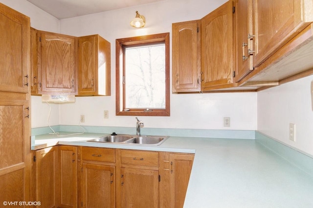 kitchen featuring brown cabinetry, light countertops, and a sink