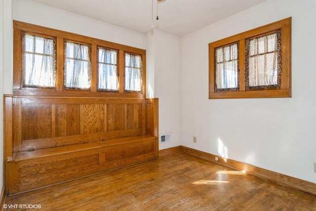 unfurnished room with a ceiling fan, baseboards, visible vents, and wood finished floors