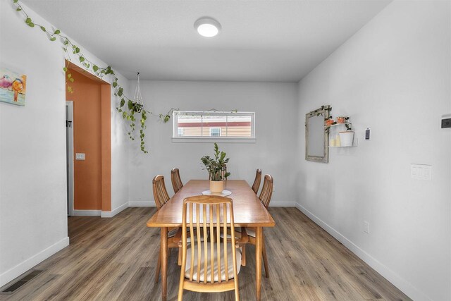 dining room with light wood-type flooring, visible vents, and baseboards