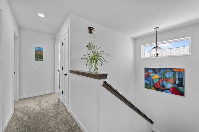 hall featuring carpet floors, an upstairs landing, and baseboards