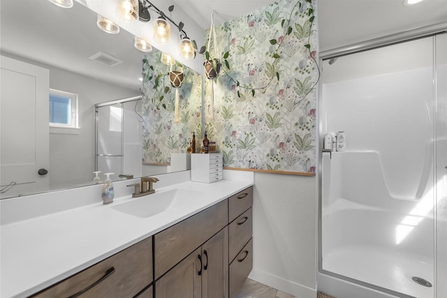 full bath with visible vents, a stall shower, vanity, and baseboards