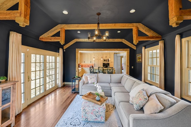 living room with plenty of natural light, lofted ceiling with beams, an inviting chandelier, and wood finished floors