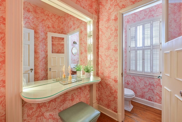 bathroom featuring wallpapered walls, toilet, wood finished floors, and baseboards