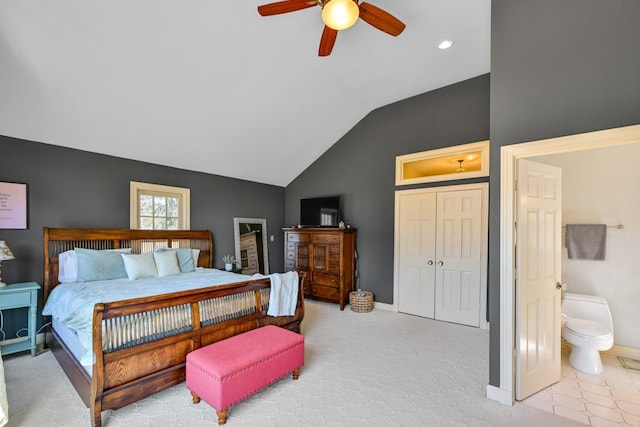 bedroom featuring baseboards, ceiling fan, vaulted ceiling, a closet, and ensuite bath