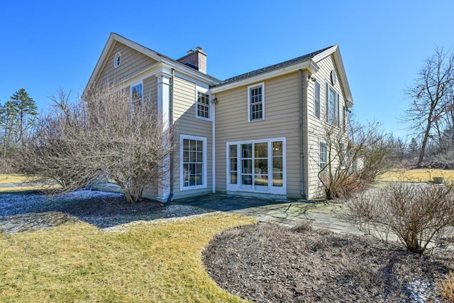 rear view of property with a patio, a yard, and a chimney