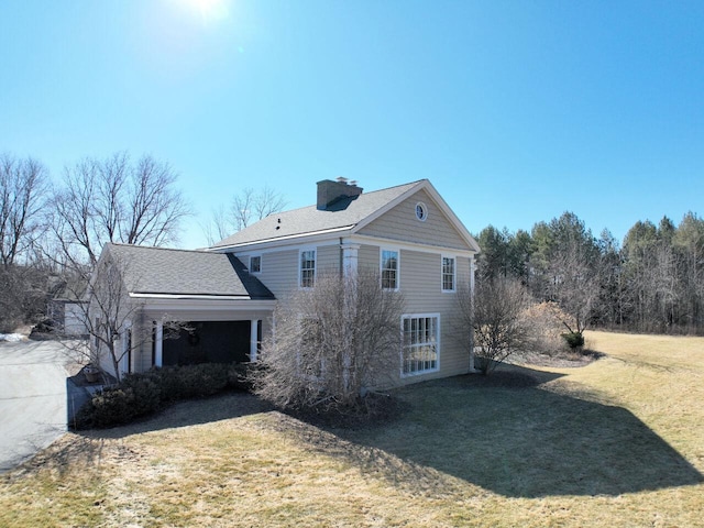 view of side of home with a yard, roof with shingles, and a chimney