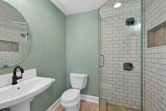 bathroom with a sink, baseboards, toilet, and a stall shower