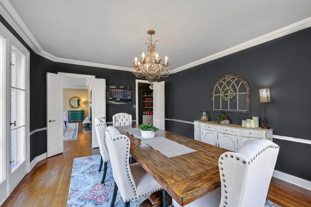 dining space featuring a notable chandelier, baseboards, wood-type flooring, and ornamental molding