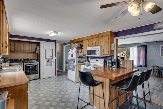 kitchen with light floors, butcher block counters, a sink, separate washer and dryer, and white appliances