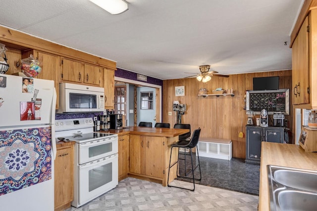 kitchen with white appliances, a sink, a peninsula, and light floors