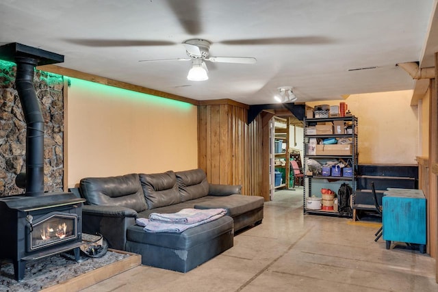 living area with a wood stove, concrete floors, and a ceiling fan