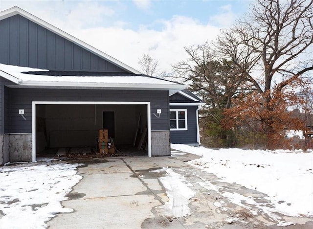 snow covered garage with driveway