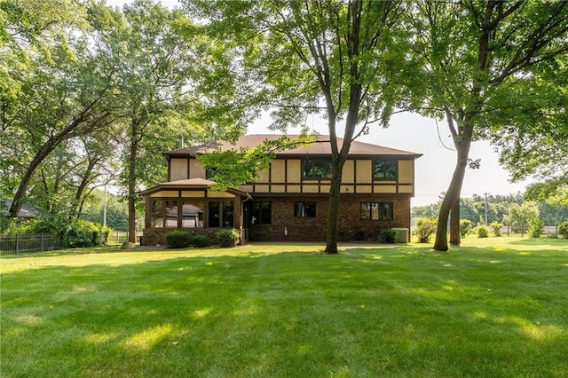 back of house featuring central AC unit, a lawn, fence, and stucco siding