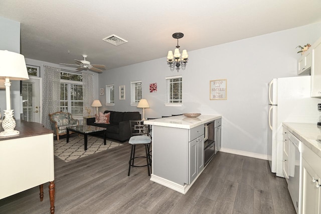 kitchen with a breakfast bar, dark wood finished floors, visible vents, open floor plan, and a peninsula