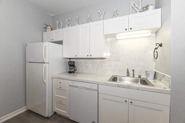 kitchen featuring white appliances, decorative backsplash, light countertops, white cabinetry, and a sink