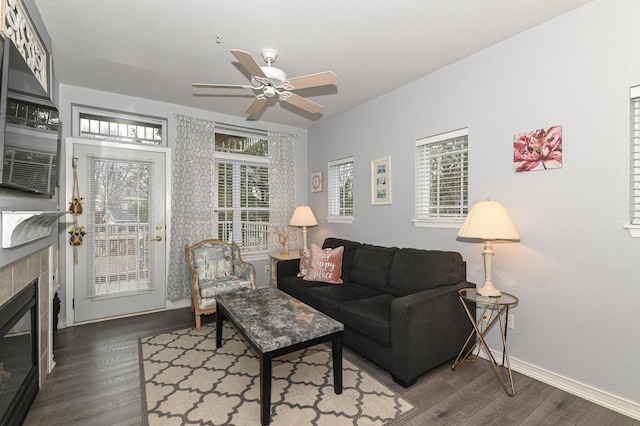 living room featuring a fireplace, wood finished floors, a ceiling fan, and baseboards