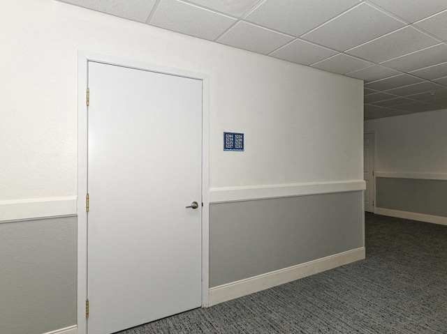 hall featuring a paneled ceiling, carpet flooring, and baseboards