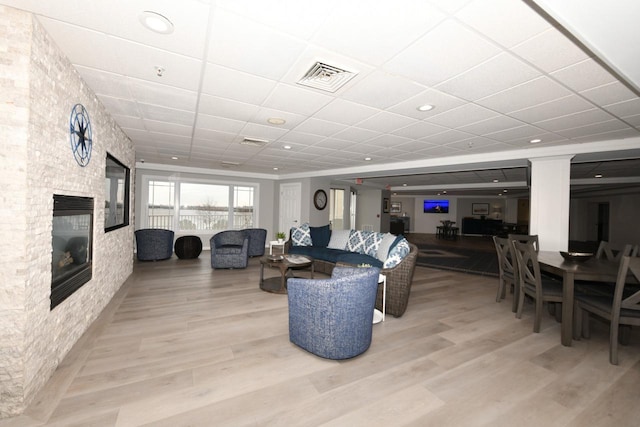 living room featuring a paneled ceiling, visible vents, a fireplace, and wood finished floors