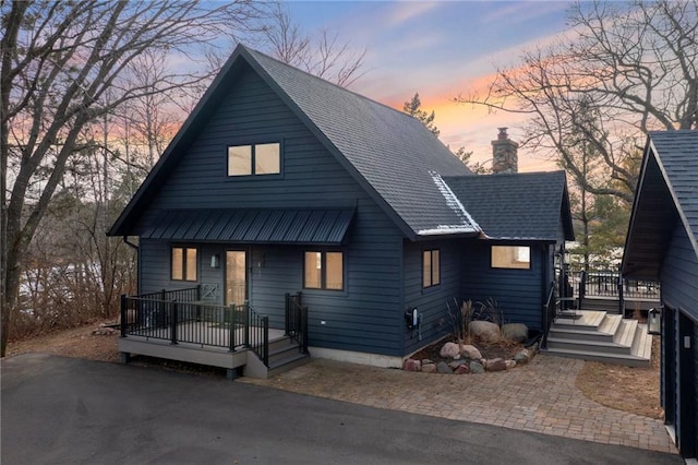 rustic home featuring a shingled roof, a chimney, and a deck