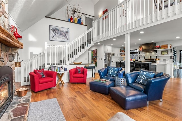 living room with stairs, a fireplace, wood finished floors, and a towering ceiling