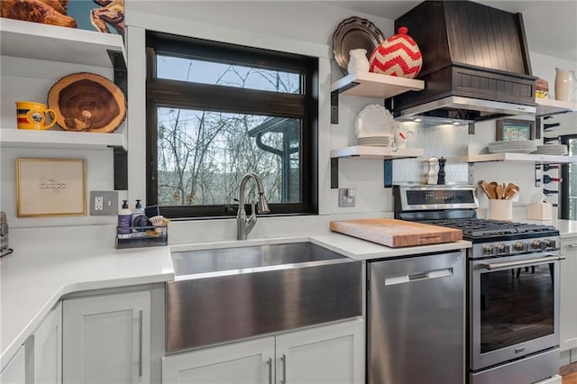 kitchen with stainless steel appliances, a sink, light countertops, open shelves, and custom range hood