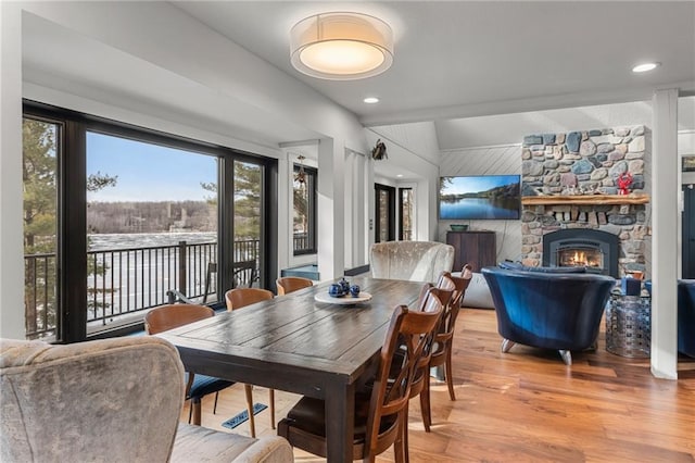 dining room with light wood-style floors and a stone fireplace