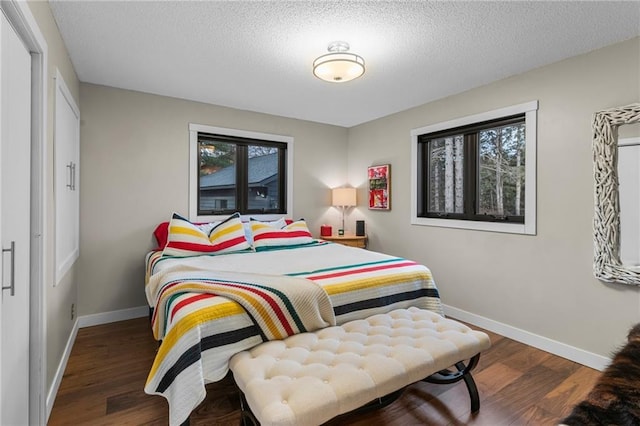 bedroom featuring a textured ceiling, baseboards, and wood finished floors