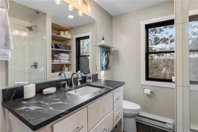 bathroom with a baseboard radiator, tiled shower, vanity, and toilet