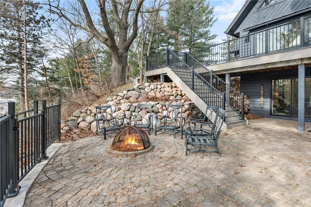 view of patio featuring a deck, a fire pit, and stairs