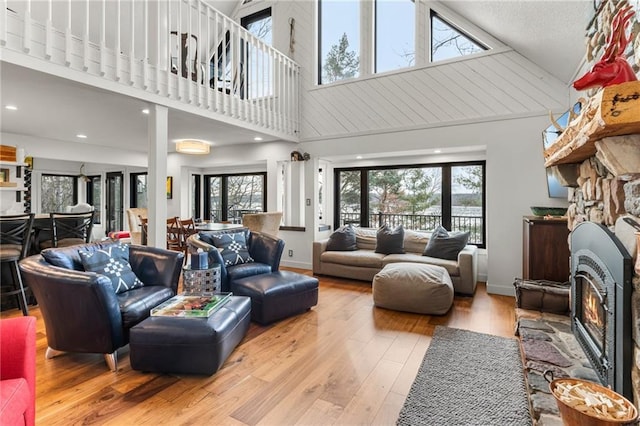 living area featuring a lit fireplace, plenty of natural light, wood finished floors, and baseboards