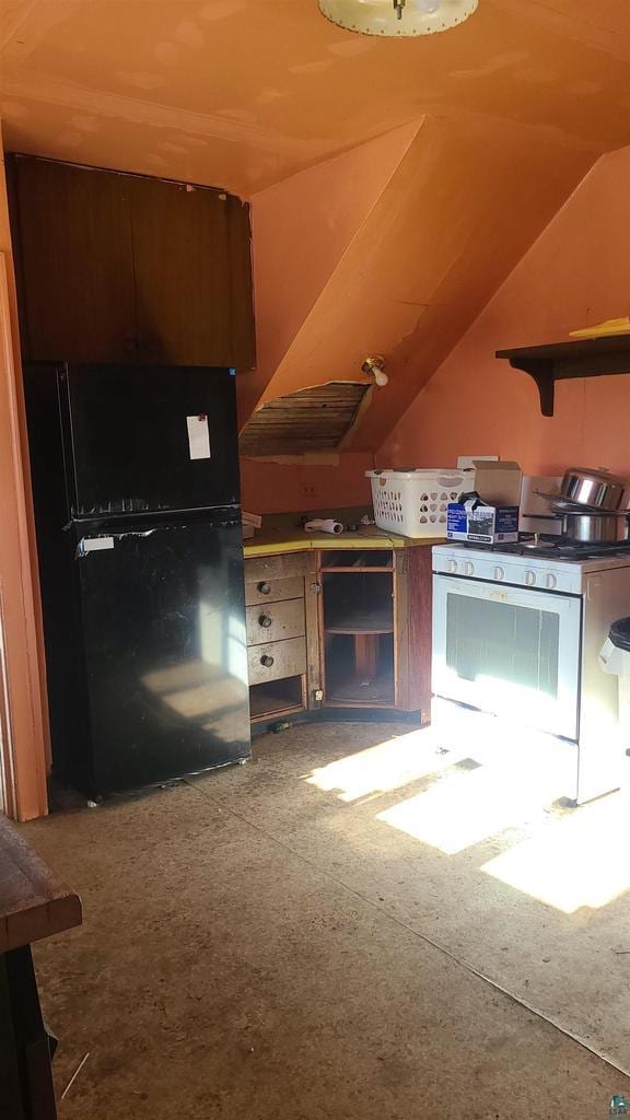 kitchen featuring lofted ceiling, white gas stove, and freestanding refrigerator