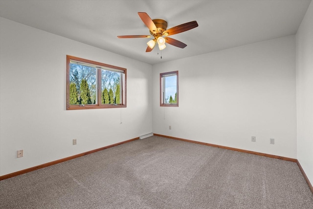 carpeted spare room featuring a ceiling fan and baseboards