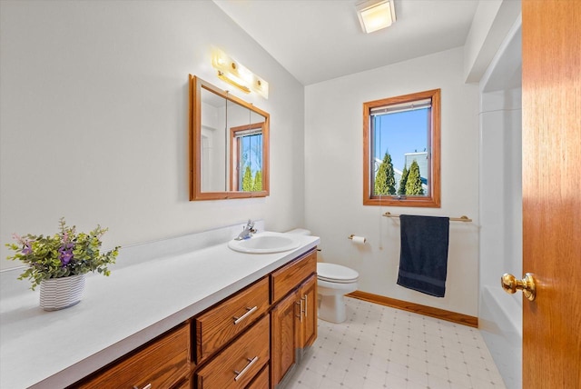 bathroom with baseboards, toilet, tile patterned floors, a bathtub, and vanity